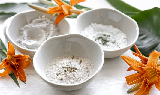 Protein powder displayed in white bowls with orange flowers and green leaves.